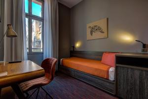 a bedroom with a bed and a desk and a window at Alex Hotel & Spa in Marseille