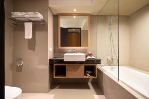 ein Badezimmer mit einem Waschbecken, einem Spiegel und einer Badewanne in der Unterkunft FOX Hotel Jimbaran Beach in Jimbaran