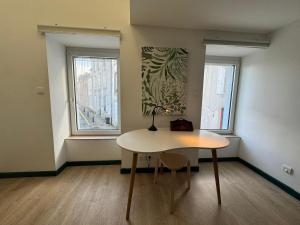 ein kleines Zimmer mit einem Tisch und 2 Fenstern in der Unterkunft Jolie maison de ville, vue mer in Le Conquet