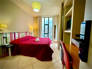 a bedroom with a red bed and a television at Hotel Le Ceramiche in Montalto Uffugo