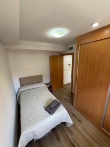 a small bedroom with a bed and a wooden door at AB Apartamentos in Melilla