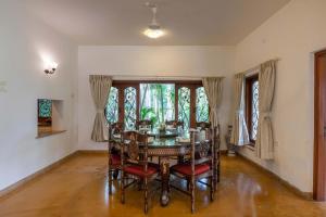 a dining room with a table and chairs and windows at Theta Villa in Alibag