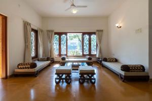 a living room with couches and a table and windows at Theta Villa in Alibag