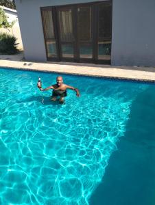 a man in a swimming pool with a bottle of beer at Van Dyk guest house in Boksburg