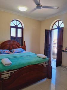 a bedroom with a bed with green sheets and two windows at Home Stay Boutique Zanzibar in Stone Town