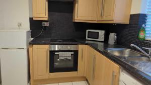 a small kitchen with a stove and a sink at Alexander Apartments High Heaton in Gosforth