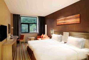 a hotel room with two beds and a desk at Wanda Momoland Changbaishan in Fusong