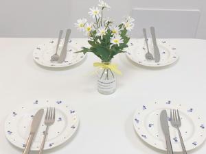 a table with plates and silverware and a vase of flowers at 2Room Jamsil lotteworld Kspo dome Olympic Park 2Queenbed in Seoul