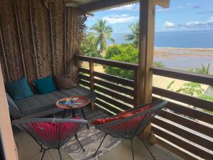 a balcony with a couch and chairs and the ocean at Coin paisible du nord in Acoua