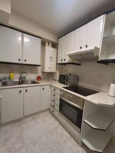 een keuken met witte kasten, een wastafel en een fornuis bij Apartamento San Antón in Huesca