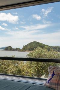 a window with a view of a river and a mountain at Haka Lodge Bay of Islands (Paihia) in Paihia