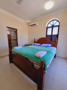 a bedroom with a large wooden bed with green sheets at Home Stay Boutique Zanzibar in Stone Town