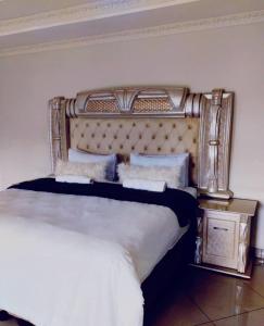 a bedroom with a large bed with a gold headboard at Rest Camp Lodge in Manzini