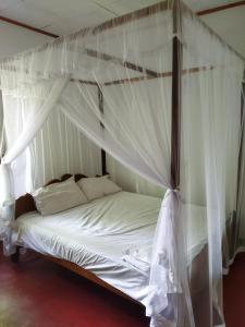 a bedroom with a canopy bed with white drapes at Guruge villa in Hikkaduwa