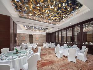 a banquet hall with white tables and chairs and a chandelier at Langham Place Guangzhou - Walking distance to Canton Fair in Guangzhou