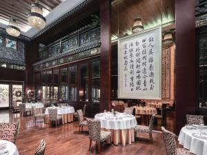 a dining room with tables and chairs and a large painting at Langham Place Guangzhou - Walking distance to Canton Fair in Guangzhou