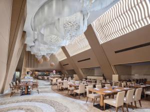 a dining room with tables and chairs and chandeliers at Langham Place Guangzhou - Walking distance to Canton Fair in Guangzhou