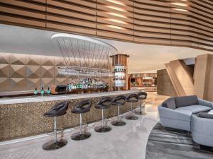a lobby with a bar with stools and a couch at Langham Place Guangzhou - Walking distance to Canton Fair in Guangzhou