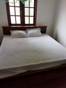 a bed with white sheets and pillows in a bedroom at Guruge villa in Hikkaduwa