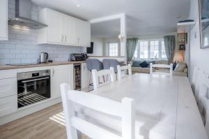 a kitchen and living room with a white table and chairs at Eddies - 2 Bedroom Chalet – Scurlage in Knelston