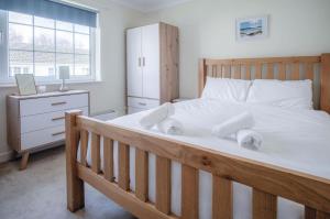 a bedroom with a large wooden bed with white sheets at Eddies - 2 Bedroom Chalet – Scurlage in Knelston
