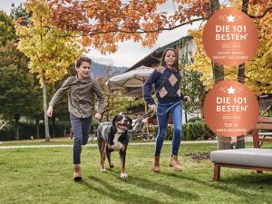 a man and a woman walking a dog in a park at Clubhaus Bachmair Weissach in Tegernsee