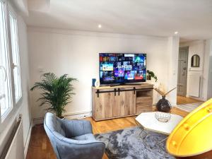 a living room with a large flat screen tv at Le chesterfield - coeur de ville in Épinal +8 photos