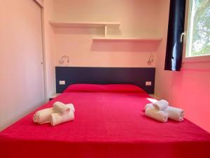 1 dormitorio con 1 cama roja y 2 toallas en Case Vacanze Uliveto, en Mattinata