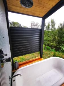 a bathroom with a window with a black shutter at Petal Creek Farm in Tarakohe