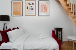 um quarto com uma cama branca com quatro fotografias na parede em Park Strzelecki Two-Level Apartment em Cracóvia
