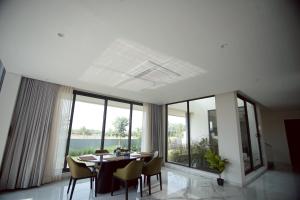 a dining room with a table and chairs and large windows at Cahaya - Beachouse 4BHK Villa with Jacuzzi & Home Theatre, 7 minute walk to the beach in Mandvi