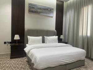 a bedroom with a large bed with white sheets and pillows at أجوان بارك للشقق المخدومة ظهرة لبن Ajwan Park For Serviced Apartments in Riyadh +26 photos
