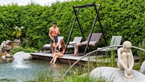 Ein Mann und eine Frau sitzen auf einer Bank in einem Teich in der Unterkunft Hotel Sun in Natz-Schabs