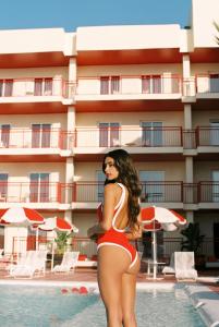 una mujer en bikini rojo parada junto a una piscina en Romeos Ibiza - Adults Only en San Antonio Bay