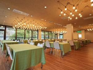 un salón de banquetes con mesas verdes, sillas y lámparas de araña en 多武峰観光ホテル, en Sakurai