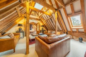 una sala de estar con muebles de cuero y techos de madera. en Huge luxury loft cottage in historic country estate - Belchamp Hall Hayloft, en Belchamp Otten