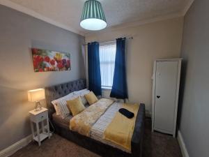 a bedroom with a bed with blue curtains and a window at Executive 2-Bedroom House in Wallsend in Wallsend