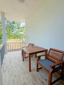 een houten tafel en stoelen in een kamer met een balkon bij Rawai Valley Resort in Rawai Beach