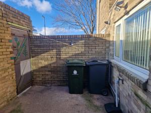 沃爾森德的住宿－Executive 2-Bedroom House in Wallsend，两个垃圾桶坐在砖墙旁边