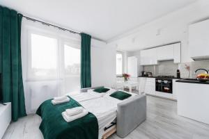 a white bedroom with a large bed with green sheets at Bella Casa Premium Apartment - 117A Kobierzynska in Krakow