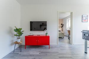 a red cabinet in a living room with a tv on a wall at E&K Apartment kleine Bandstraße in Wuppertal