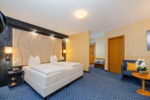 ein Hotelzimmer mit einem Bett und einem Stuhl in der Unterkunft PLAZA INN Köln Pulheim in Pulheim