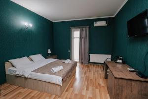 1 dormitorio con 1 cama grande y paredes verdes en Hotel Darchi, en Tiflis