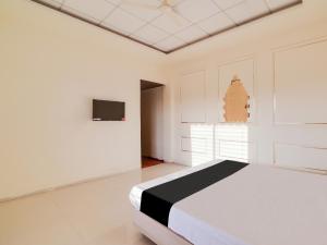 a white room with a bed and a tv at OYO Saubhagya Shri Resort in Hoshangābād