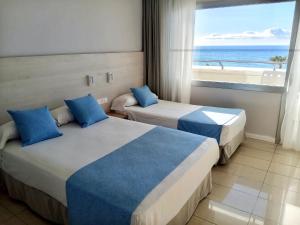 two beds in a hotel room with a view of the ocean at URH Excelsior in Lloret de Mar