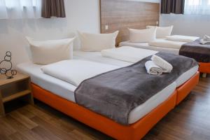 2 camas en una habitación de hotel con almohadas en Orange Hotel und Apartments, en Neu-Ulm