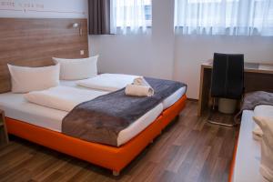 ein Hotelzimmer mit einem Bett mit einem Teddybär darauf in der Unterkunft Orange Hotel und Apartments in Neu Ulm