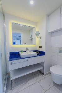 a bathroom with a sink and a mirror and a toilet at Orbi City with Sea View in Batumi