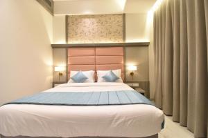 een slaapkamer met een groot wit bed met blauwe kussens bij La Dhalia By Glitz Hotels in Thane