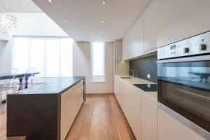 a kitchen with white cabinets and a black counter top at Chic 2-bedroom home - Richmond upon Thames in London